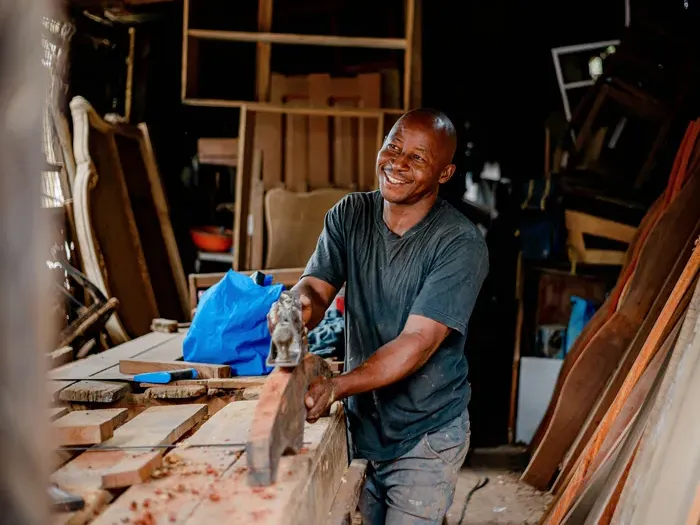 Smiling carpenter shaping wood at a workbench in a workshop, showcasing skilled trades on City Directory Go